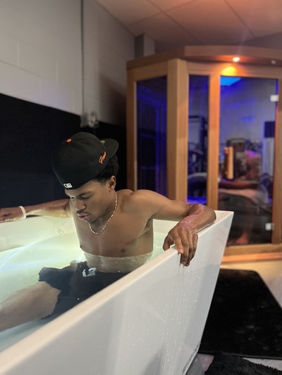 Boy in cold tub with infrared sauna in background