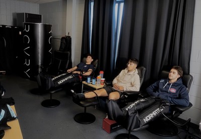 3 boys sitting in massage chairs using compression equipment on their legs